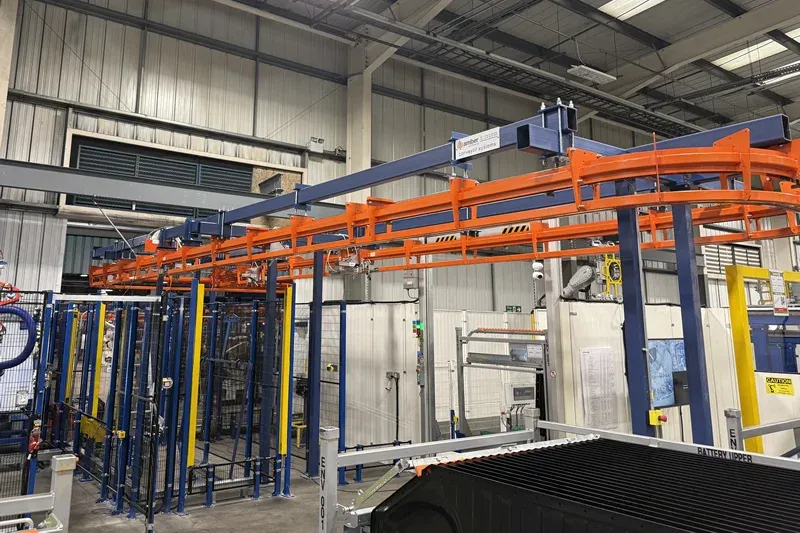 MCM Autotrack orange overhead conveyor track supported by blue steel framework in an automotive production facility